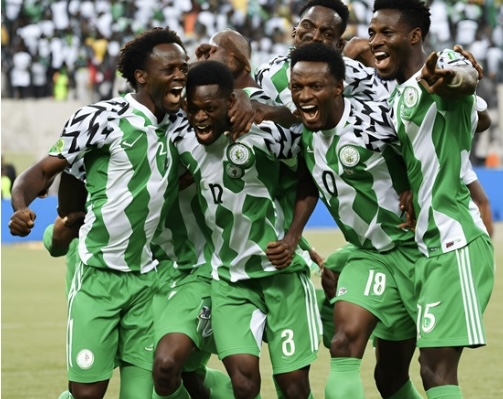 The Super Eagles celebrate passionately after scoring a goal during one of the AFCON qualifiers. The vibrant green and white of their jerseys contrasts with the cheering crowd in the background, emphasizing the energy of the moment as they strive for victory in the Africa Cup of Nations.