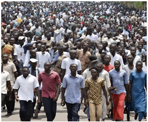 A group of Nigerians protesting in the streets against the ongoing Rivers crisis. Demonstrators call for peace and justice, expressing their concerns about the impact of the crisis on their community. The scene captures the urgency and determination of the protesters as they rally for change amidst a tense atmosphere.